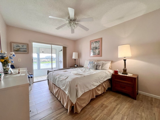 bedroom with light hardwood / wood-style floors, a textured ceiling, and ceiling fan