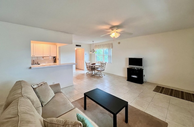 tiled living room with ceiling fan with notable chandelier