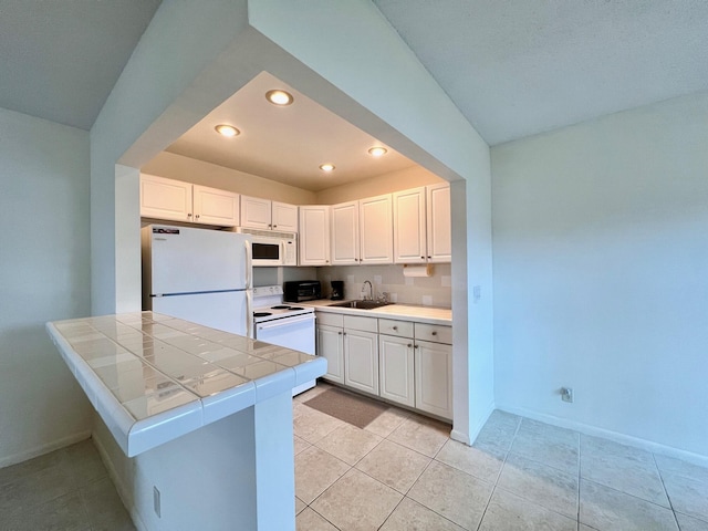 kitchen with tile countertops, sink, white cabinets, and white appliances