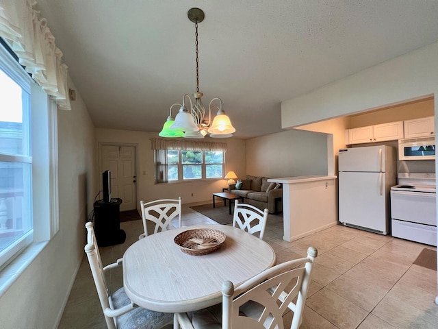 dining space featuring light tile patterned flooring, plenty of natural light, and an inviting chandelier