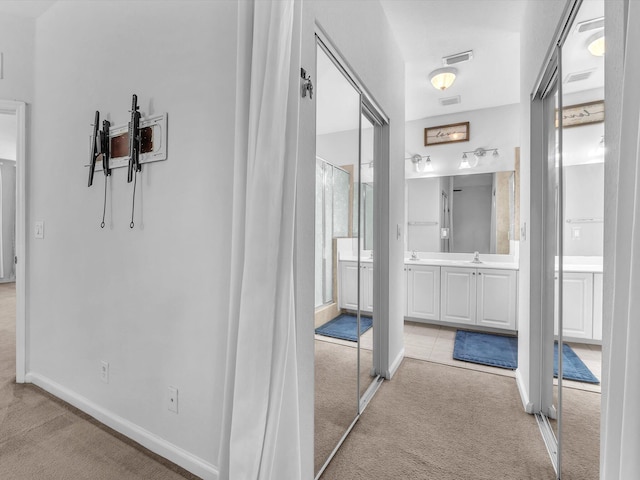 hall with light colored carpet and sink