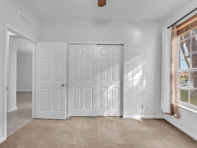 unfurnished bedroom with light carpet, a closet, and ceiling fan