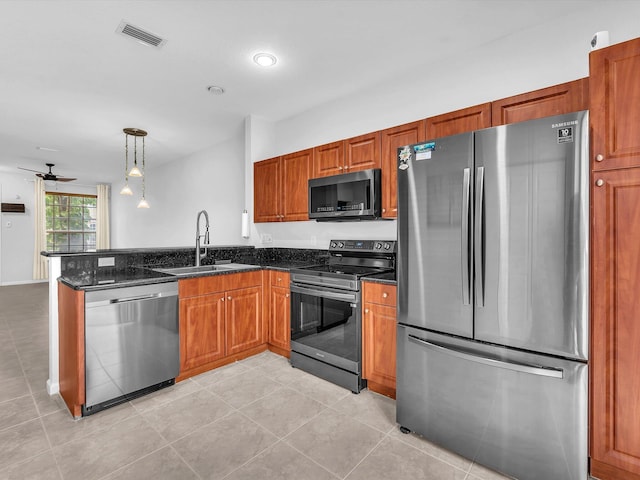 kitchen with ceiling fan, pendant lighting, sink, stainless steel appliances, and dark stone counters