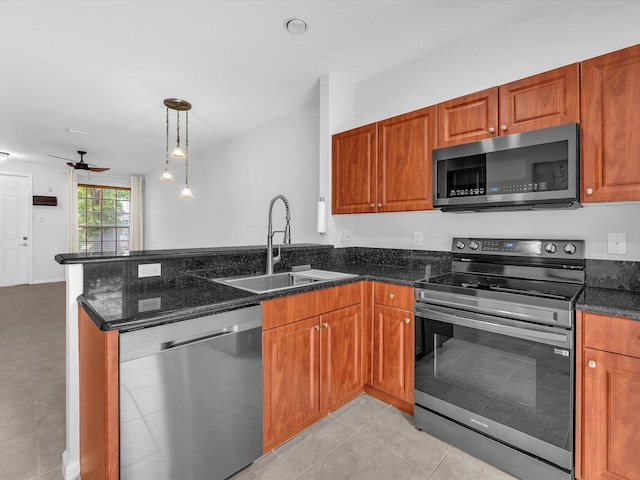 kitchen featuring stainless steel appliances, dark stone countertops, sink, hanging light fixtures, and ceiling fan