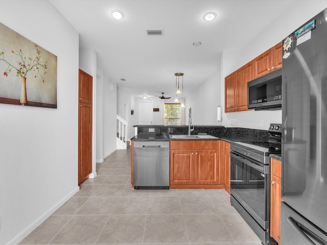 kitchen featuring ceiling fan, stainless steel appliances, decorative light fixtures, dark stone counters, and sink