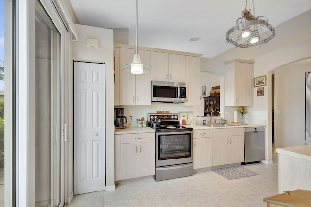 kitchen with light tile patterned floors, stainless steel appliances, sink, and pendant lighting