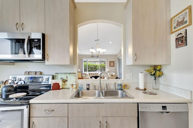 kitchen featuring light brown cabinetry, sink, stainless steel appliances, pendant lighting, and a chandelier