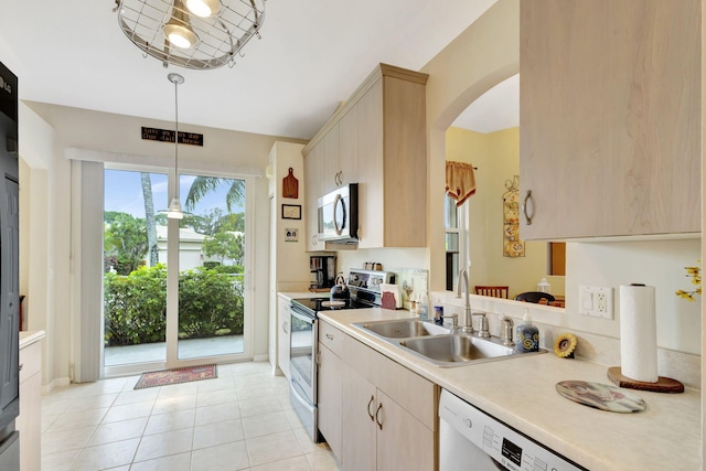 kitchen featuring light brown cabinetry, sink, pendant lighting, and white appliances