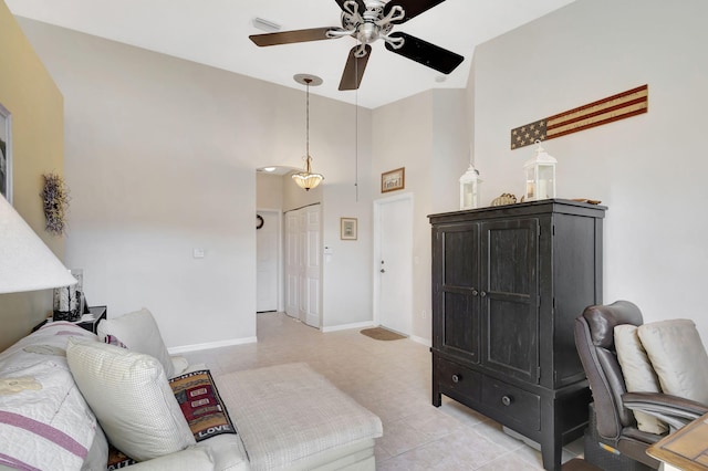 living room featuring ceiling fan, light tile patterned floors, and a high ceiling