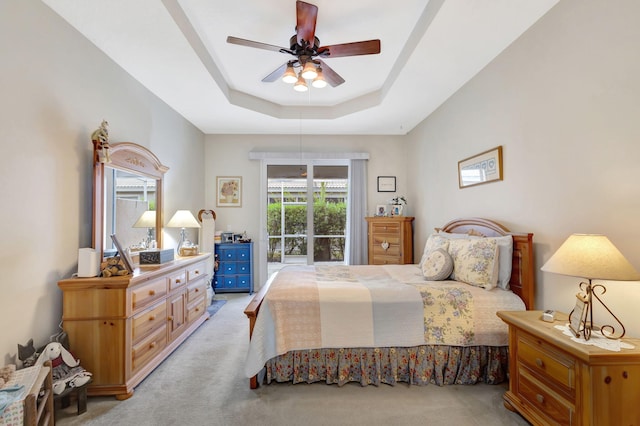 carpeted bedroom with a tray ceiling and ceiling fan