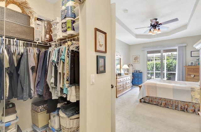 carpeted bedroom with a closet, ceiling fan, and a tray ceiling