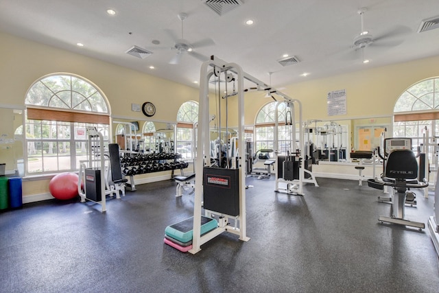 exercise room with ceiling fan and a towering ceiling