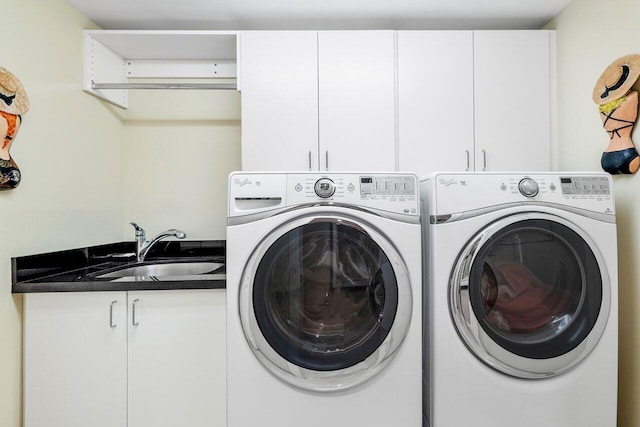 washroom featuring sink, washer and dryer, and cabinets