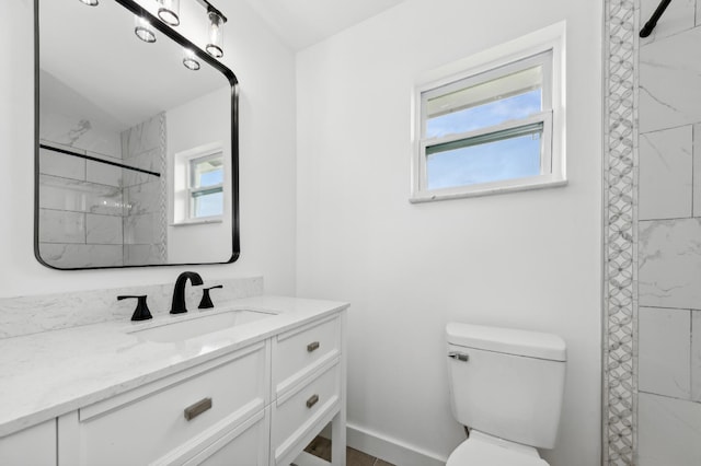 bathroom featuring a wealth of natural light, tiled shower, toilet, and vanity