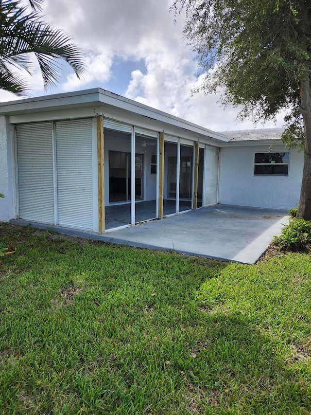 back of house featuring a lawn and a patio