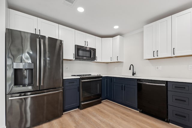 kitchen featuring light wood-type flooring, appliances with stainless steel finishes, sink, and white cabinets