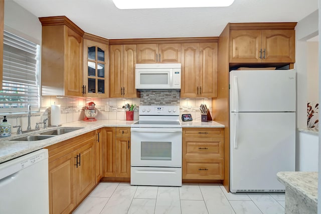 kitchen featuring white appliances, backsplash, sink, and light stone counters