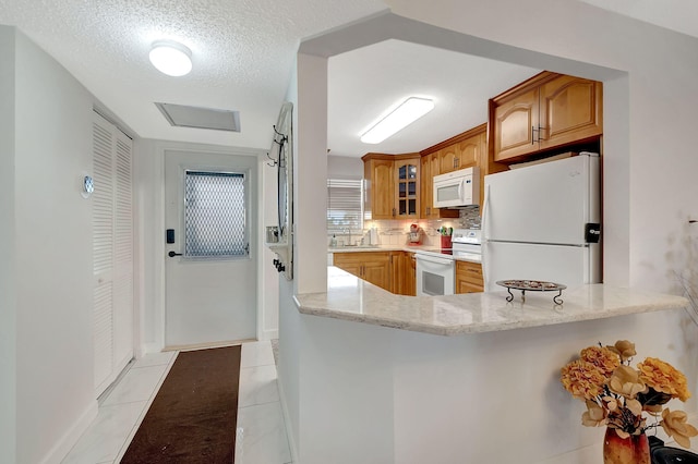 kitchen with light tile patterned floors, a textured ceiling, light stone countertops, sink, and white appliances