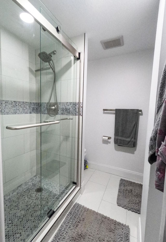 bathroom featuring toilet, an enclosed shower, and tile patterned floors