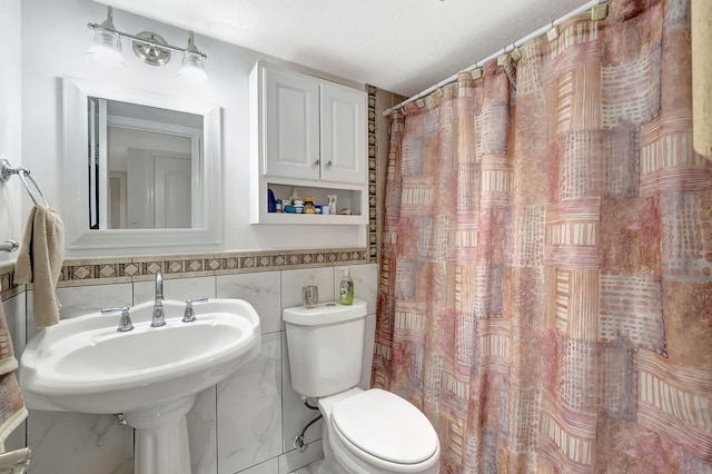 bathroom featuring toilet, sink, a shower with shower curtain, tile walls, and a textured ceiling