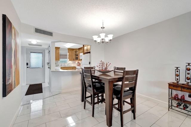 tiled dining space with a notable chandelier and a textured ceiling