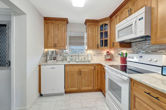 kitchen with sink, light stone counters, white appliances, and tasteful backsplash