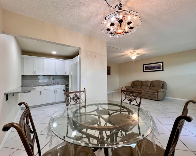 dining area featuring a notable chandelier, a textured ceiling, sink, and light tile patterned floors