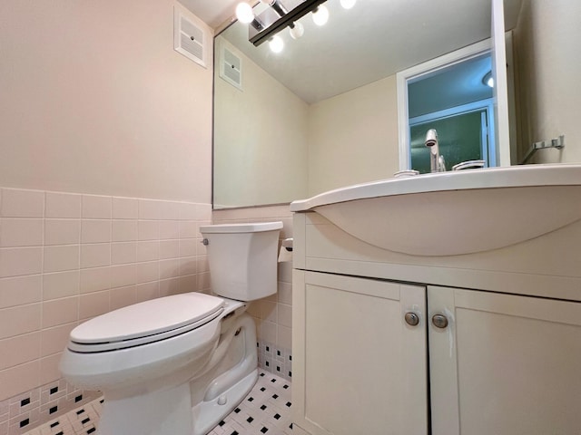 bathroom with vanity, toilet, tile patterned floors, and tile walls