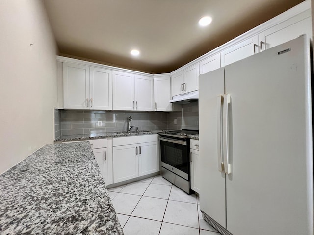 kitchen featuring backsplash, stainless steel electric range, white cabinets, white fridge, and dark stone countertops