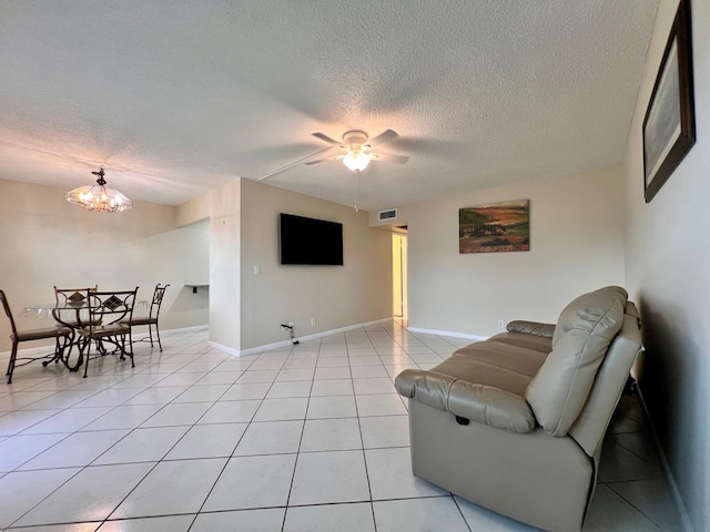 tiled living room featuring a textured ceiling and ceiling fan with notable chandelier