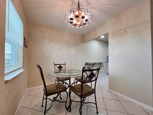 tiled dining space with a textured ceiling and a chandelier