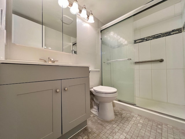 bathroom featuring toilet, vanity, and a shower with door