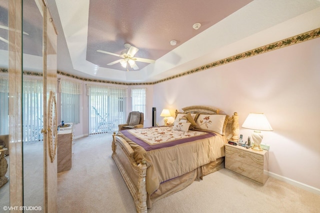 bedroom featuring light colored carpet, a tray ceiling, and ceiling fan