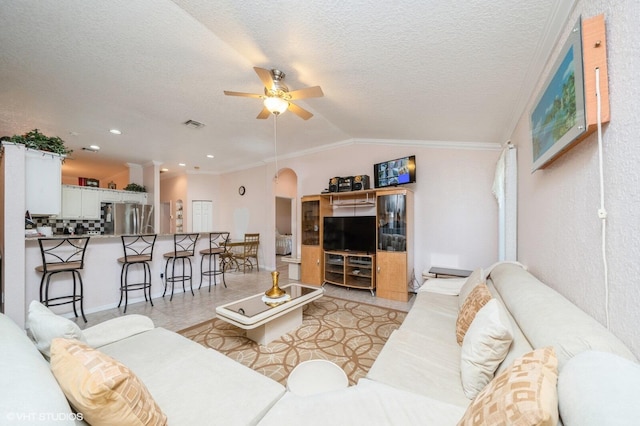 living room with ornamental molding, vaulted ceiling, a textured ceiling, and ceiling fan