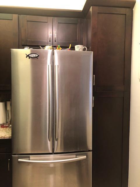 interior details with light stone counters, dark brown cabinets, and stainless steel refrigerator