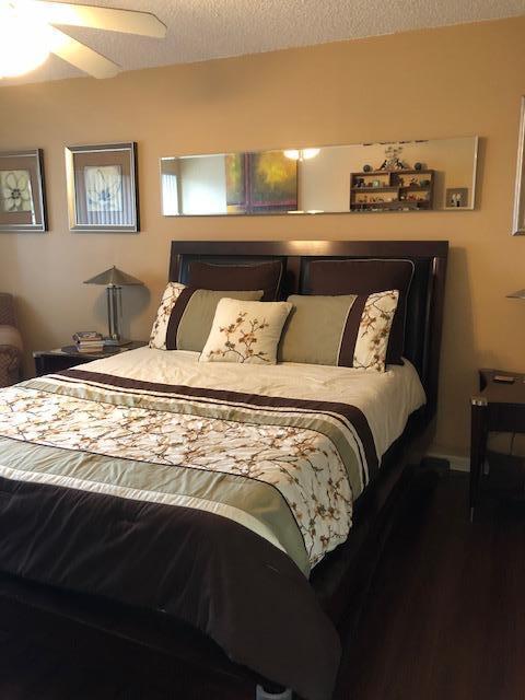 bedroom with a textured ceiling, wood-type flooring, and ceiling fan