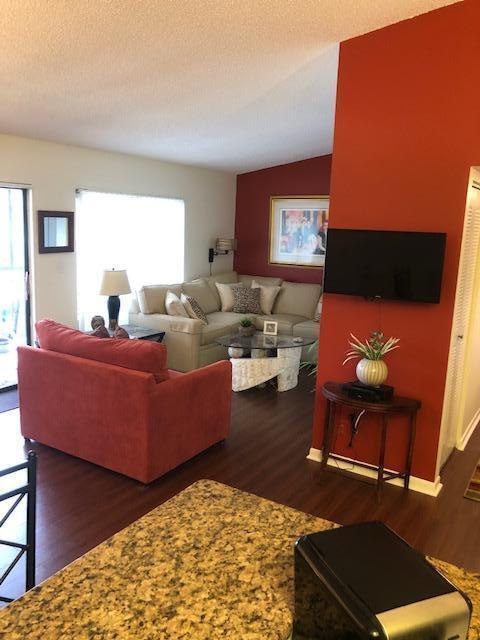 living room with lofted ceiling, dark wood-type flooring, and a textured ceiling