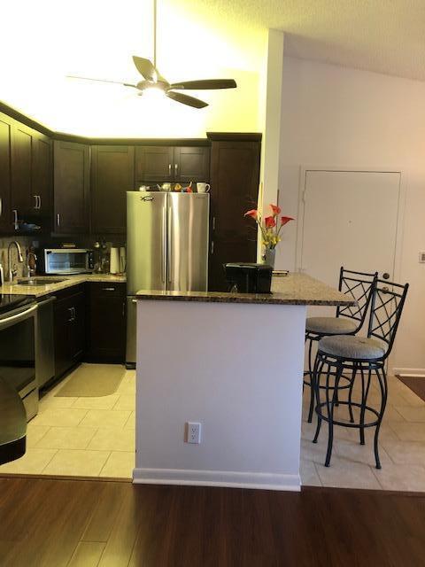 kitchen featuring a kitchen island, a breakfast bar area, dark stone counters, sink, and light wood-type flooring