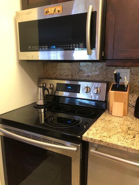 kitchen featuring light stone countertops, dark brown cabinetry, stainless steel appliances, and tasteful backsplash