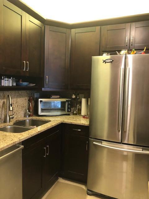 kitchen with dark brown cabinets, light stone countertops, stainless steel appliances, and sink