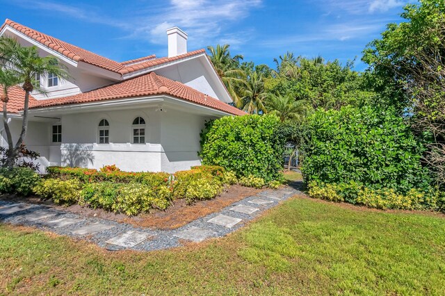 930 N Parkside Cir N, Boca Raton, FL 33486 - view of home's exterior with a tile roof, a lawn, a chimney, and stucco siding