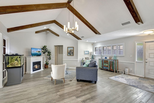 living room featuring a textured ceiling, hardwood / wood-style floors, beam ceiling, high vaulted ceiling, and an inviting chandelier