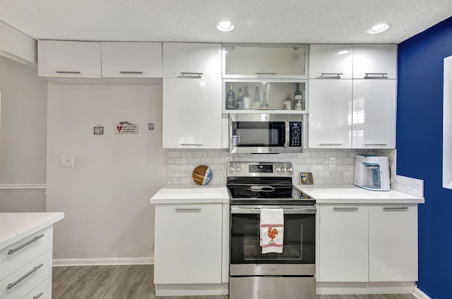 kitchen featuring light stone counters, appliances with stainless steel finishes, decorative backsplash, and white cabinets