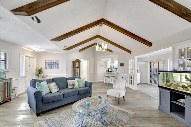 living room with vaulted ceiling with beams, hardwood / wood-style floors, a chandelier, and plenty of natural light