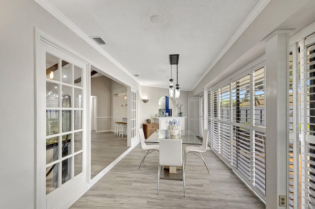 dining space featuring light hardwood / wood-style floors, crown molding, and a textured ceiling