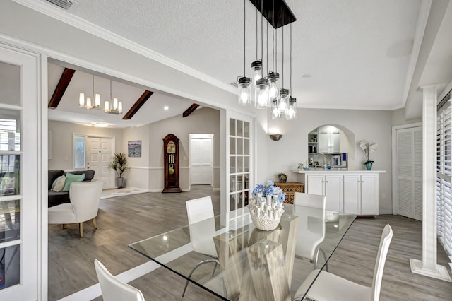 dining space with hardwood / wood-style flooring, a textured ceiling, an inviting chandelier, and vaulted ceiling with beams