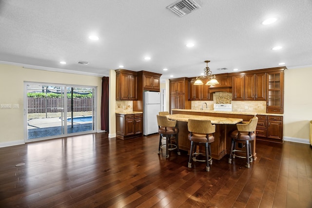100 SW 15th Ct, Boca Raton, FL 33486 - kitchen with crown molding, dark wood finished floors, backsplash, visible vents, and freestanding refrigerator