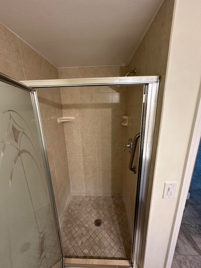 bathroom with a textured ceiling and an enclosed shower