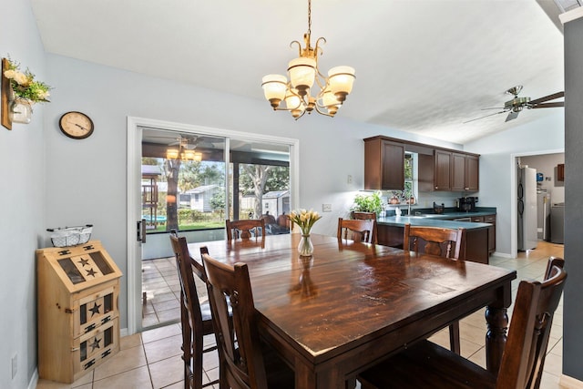 tiled dining room with ceiling fan with notable chandelier, sink, and vaulted ceiling