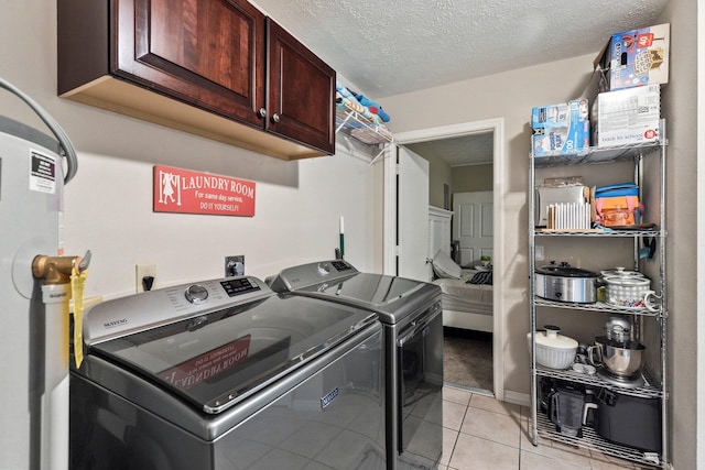 laundry room featuring washer and clothes dryer, cabinets, light tile patterned floors, and a textured ceiling